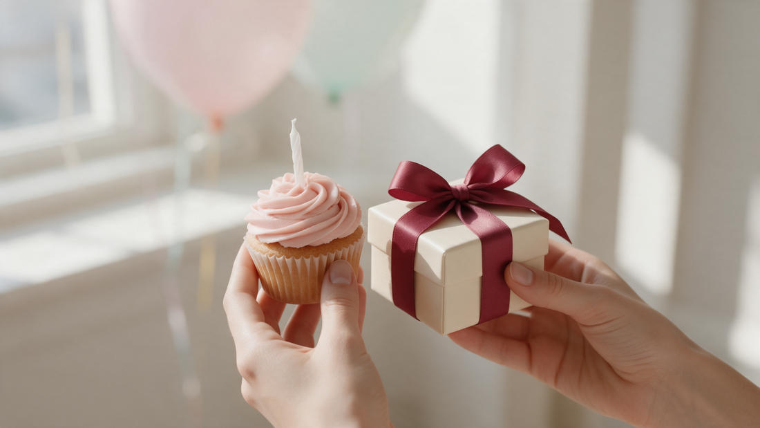 A birthday cupcake and a small gift box with a burgundy ribbon