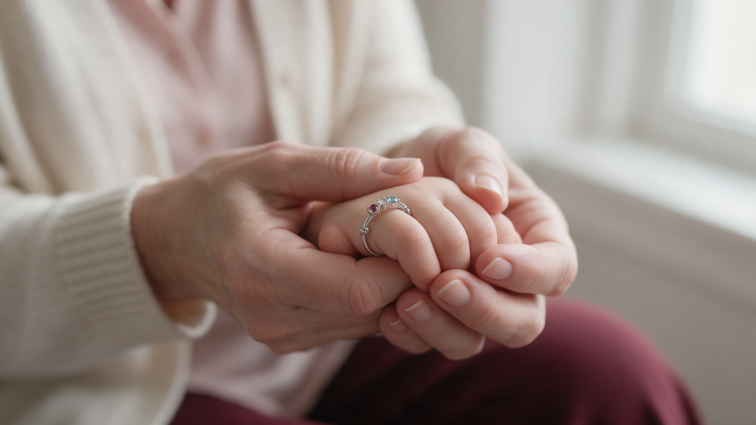 A grandmother's hands holding a grandchild's hand with a silver birthstone ring
