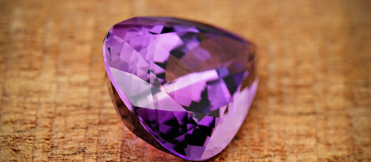 Close-up of a sparkling purple amethyst gemstone on a textured surface