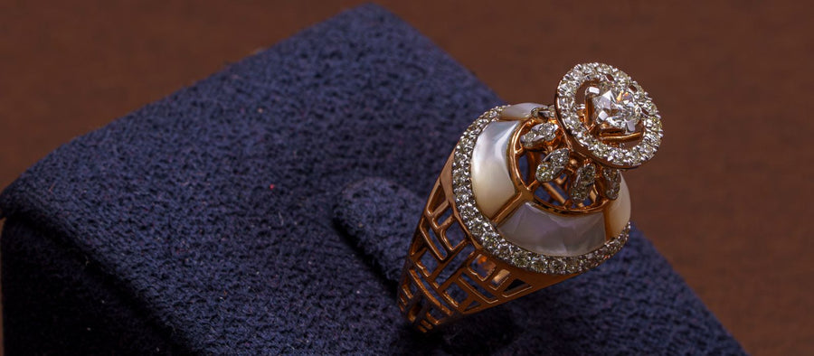 Ornate rose gold ring set with clear stones displayed on a navy velvet stand