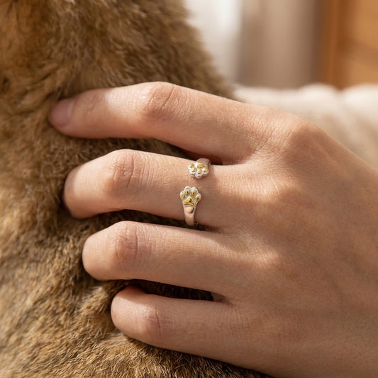 Adjustable cat paw print ring with two gold paw prints worn while petting a cat