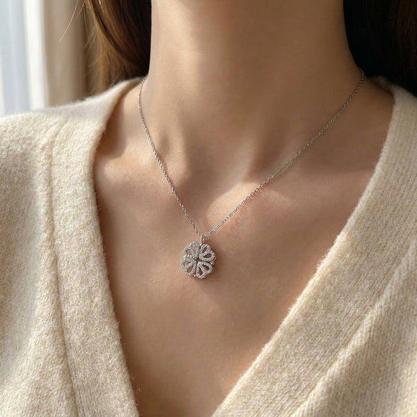 Silver four-leaf clover pendant made of four heart-shaped leaves with tiny clear stones, worn on a fine silver chain (styled lifestyle photo)